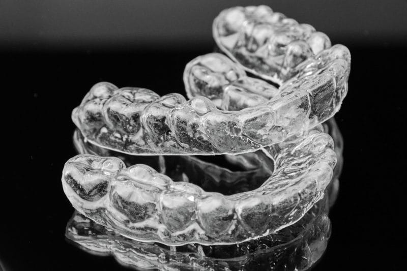 Invisalign in Oakland, NJ, on a black background.